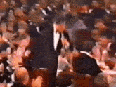 a man in a suit and tie is standing in front of a crowd of people .
