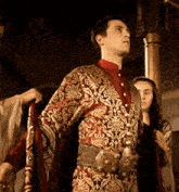 a man in a red and gold costume with a gold belt is standing next to a woman