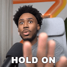 a man sitting in front of a microphone with his hands up and the words hold on above him