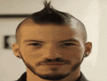 a man with a mohawk and a beard is smiling .