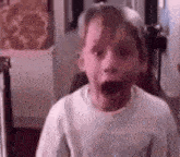 a young boy is making a funny face with his mouth wide open .