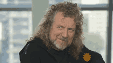 a man with long curly hair and a beard wears a black hoodie