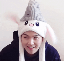 a man wearing a hat with bunny ears and a smiley face on it