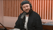 a man with a beard is sitting in front of a microphone wearing headphones .