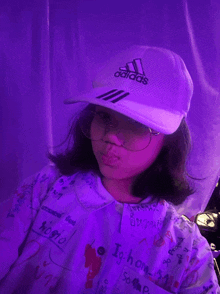 a girl wearing a white adidas hat and a purple shirt