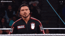a man in a wrestling ring wearing a jacket that says page