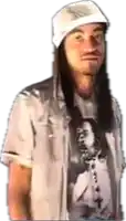 a man with long hair is wearing a white hat and a t-shirt with a picture of jesus on it .