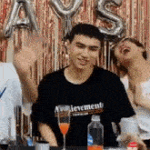 a group of young men are sitting at a table with balloons behind them .