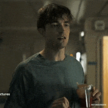 a man in a green shirt is holding a pitcher of liquid .