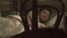 a man is sleeping in a bed with a clock that says 7:37