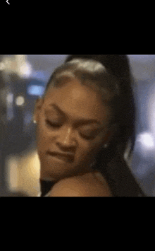 a close up of a woman 's face with a ponytail making a funny face .