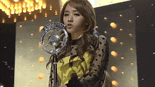 a woman stands in front of a microphone that says u.r.a.d.e.f. on it