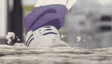 a person wearing purple pants and white shoes is running on a rocky surface