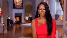 a woman in a red dress is sitting in a living room with her head down .