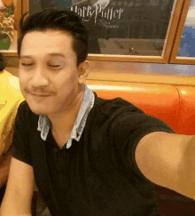 a man wearing a harry potter shirt is taking a selfie with his eyes closed