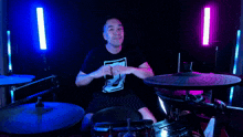 a man making a heart shape with his hands in front of drums