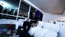 a man wearing a black givenchy shirt sits on a white couch