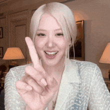a woman with blonde hair is smiling and pointing her finger up