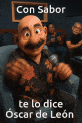 a man with a mustache is singing into a microphone with the words con sabor te lo dice oscar de leon below him