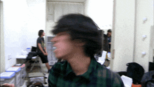 a blurry picture of a man in a plaid shirt standing in a room
