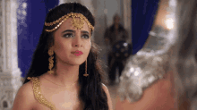 a woman wearing a headpiece and earrings looks at the camera