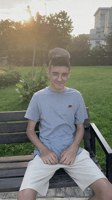 a young man sitting on a bench wearing a nike shirt