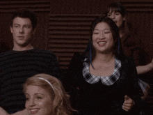 a group of people are sitting in a row and one of them is wearing a plaid shirt