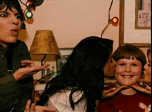 a woman kisses a boy on the cheek in a room with a lamp