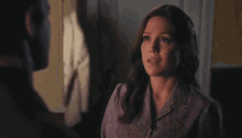a woman in a purple shirt is saying everything in a dark room .