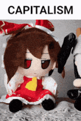 a stuffed doll is sitting next to another stuffed doll with the word capitalism written above it