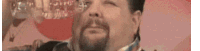 a man with a beard is drinking a glass of water .