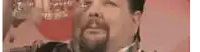 a man with a beard is drinking a glass of water .