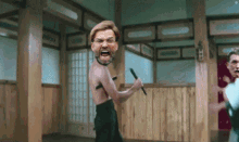 a man without a shirt is holding a sword in his hand