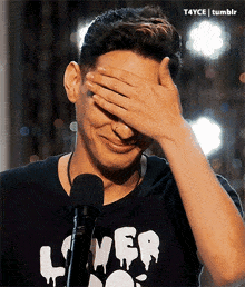 a man wearing a shirt that says lover covering his face with his hand