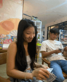 a woman in a white shirt with the word essentials on it sits next to a man in a white shirt