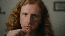 a close up of a man with long red hair eating something with a fork .