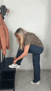 a woman wearing a leopard print shirt is tying her shoes