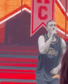 a man in a lakers jersey is singing into a microphone while standing on a stage .