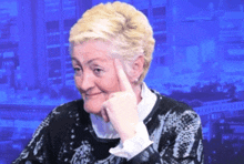 a woman with blonde hair holds her hand to her forehead