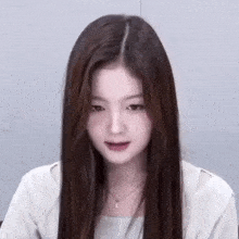 a close up of a woman with long hair wearing a necklace and a white shirt .