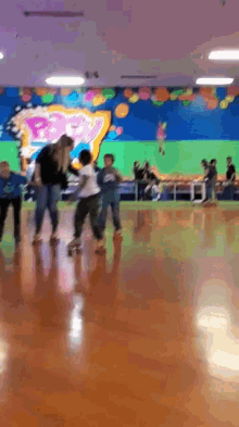 a group of people are rollerblading in a rink with a mural on the wall that says ' baby ' on it