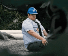 a man wearing a blue hard hat has a badge that says ' r. ' on it