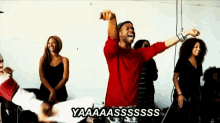 a man in a red shirt is dancing in front of a group of women and says yaaaassss