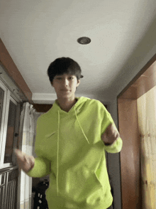 a person in a neon green hoodie is dancing in a hallway