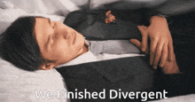 a man in a suit and tie is laying on a bed with the words we finished divergent