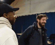 two men are standing next to each other and one has a beard