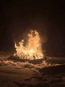 a large fire is burning in the snow in the dark