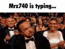 a man in a tuxedo and bow tie is sitting in front of a crowd and says ' mrz740 is typing ...