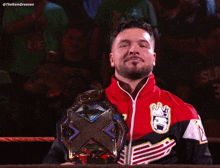 a man in a red and black jacket holds a wrestling championship