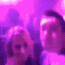 a blurry photo of a man and a woman in a purple light